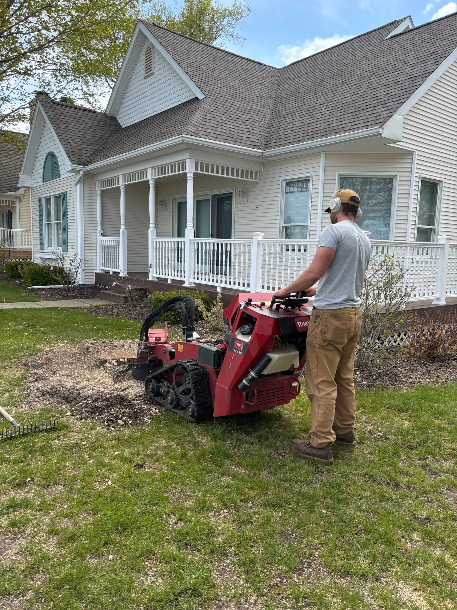 Stump grinder at work in a front yard — Up North Tree Care, Manistee, MI